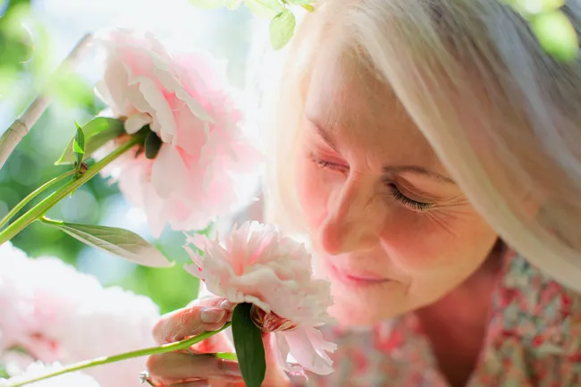 photo of mature woman smelling roses