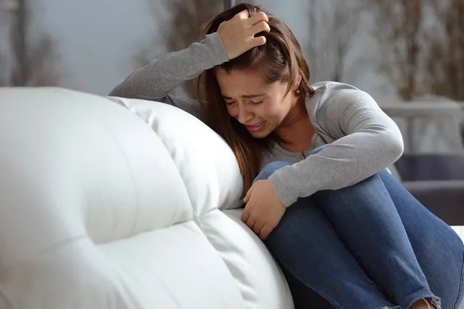 photo of woman crying on couch