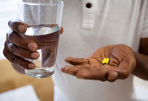hands holding glass of water and pills