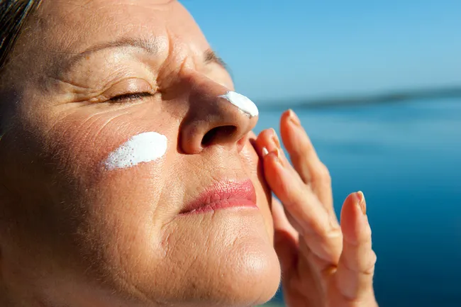 photo of mature woman applying sunscreen