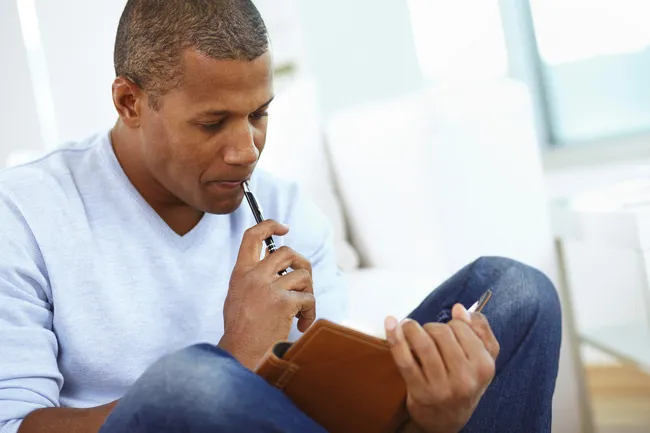 man writing in journal