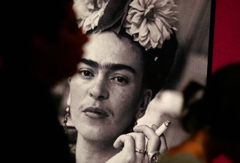 Visitors walk past photograph of Frida Kahlo