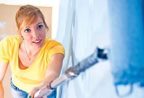 young woman painting wall