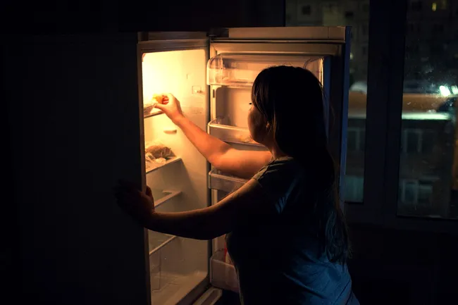 photo of woman getting food from fridge