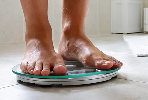 man on weight scale at home