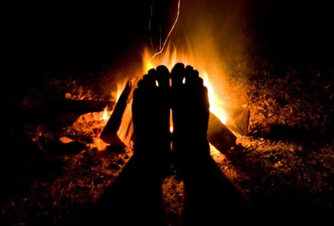 feet warmed by campfire
