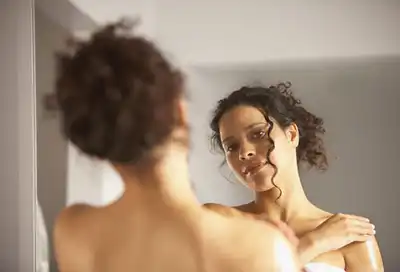 woman applying lotion while looking in mirror