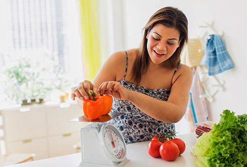 woman weighing vegetables in kitchen