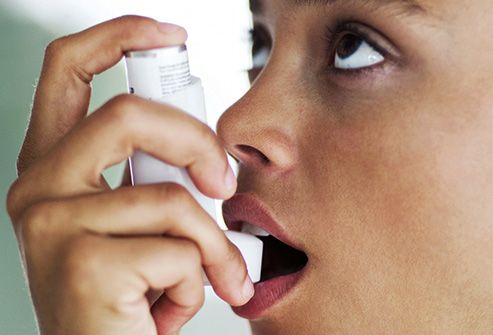woman using asthma inhaler