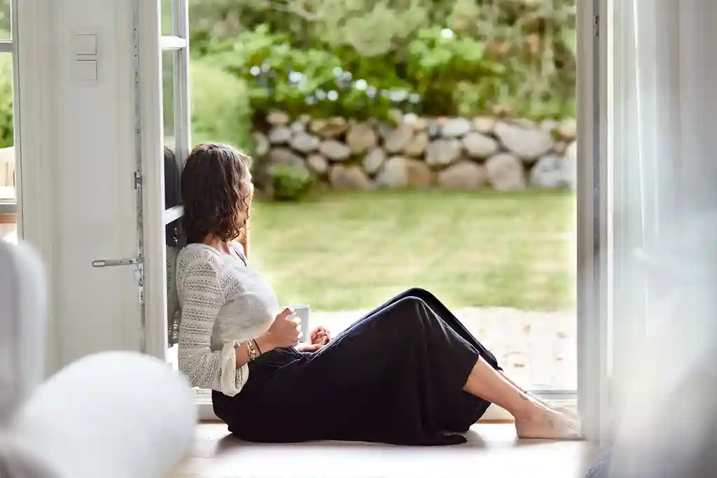 photo of woman sitting on window frame