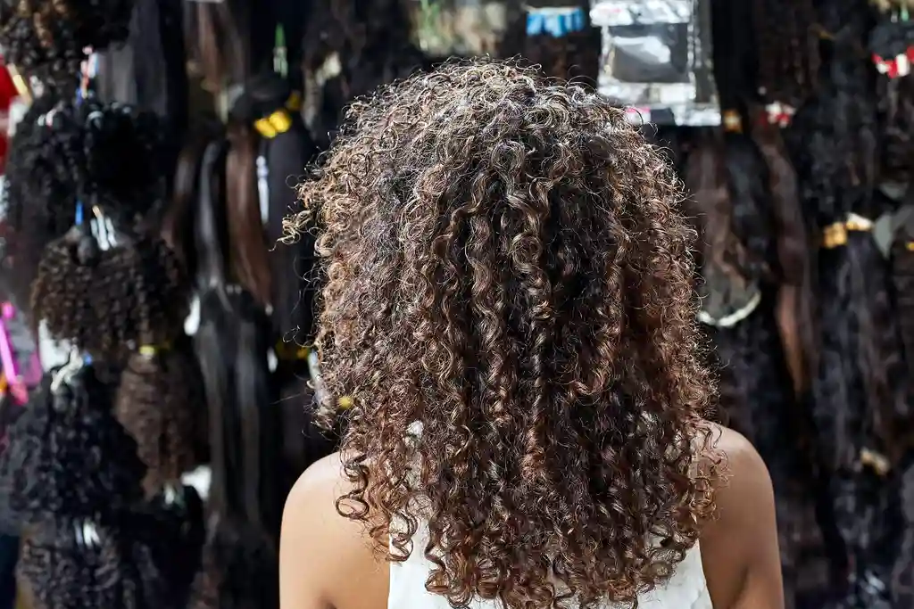 photo of young woman with curly hair in wig shop