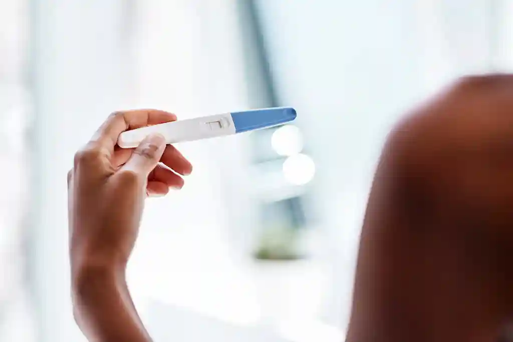 photo of woman looking at pregnancy test