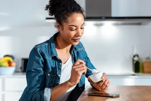 photo of woman eating yogurt in kitchen