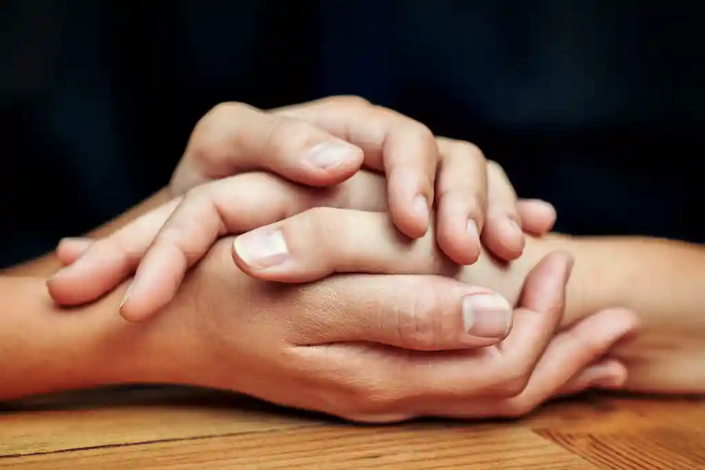 photo of close up of two people holding hands