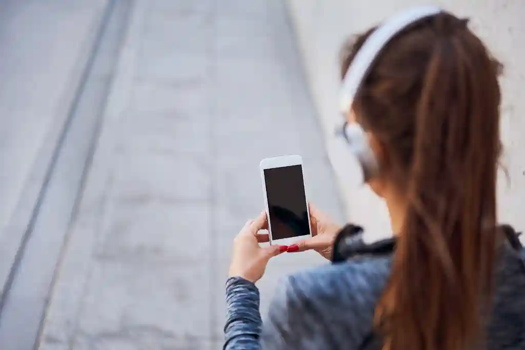 photo of woman with headphones using smartphone