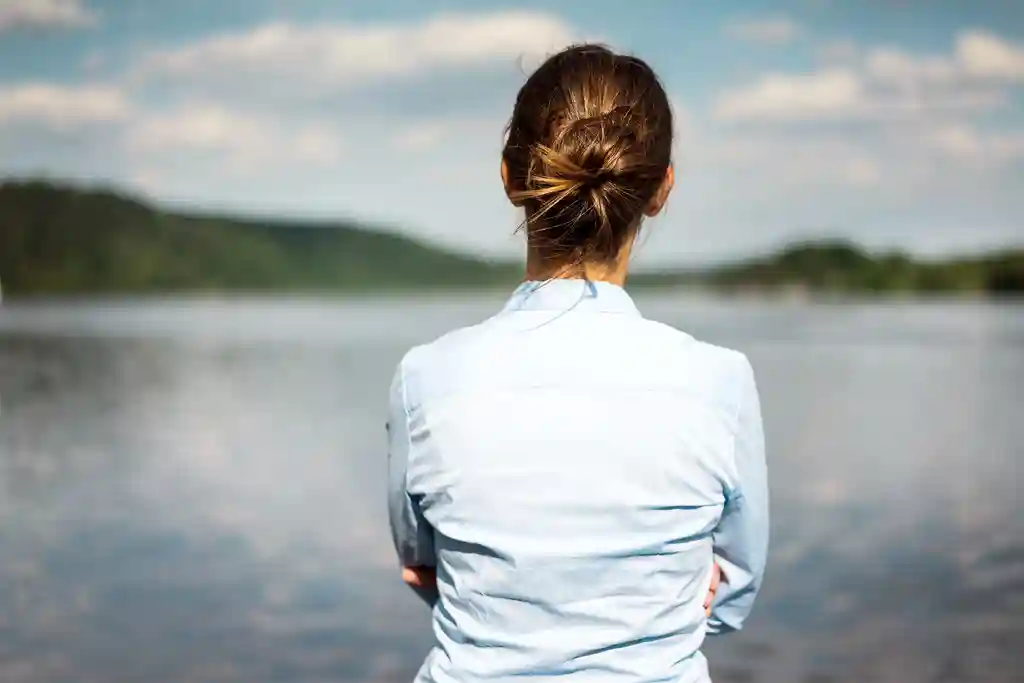 photo of rear view of woman looking at a lake