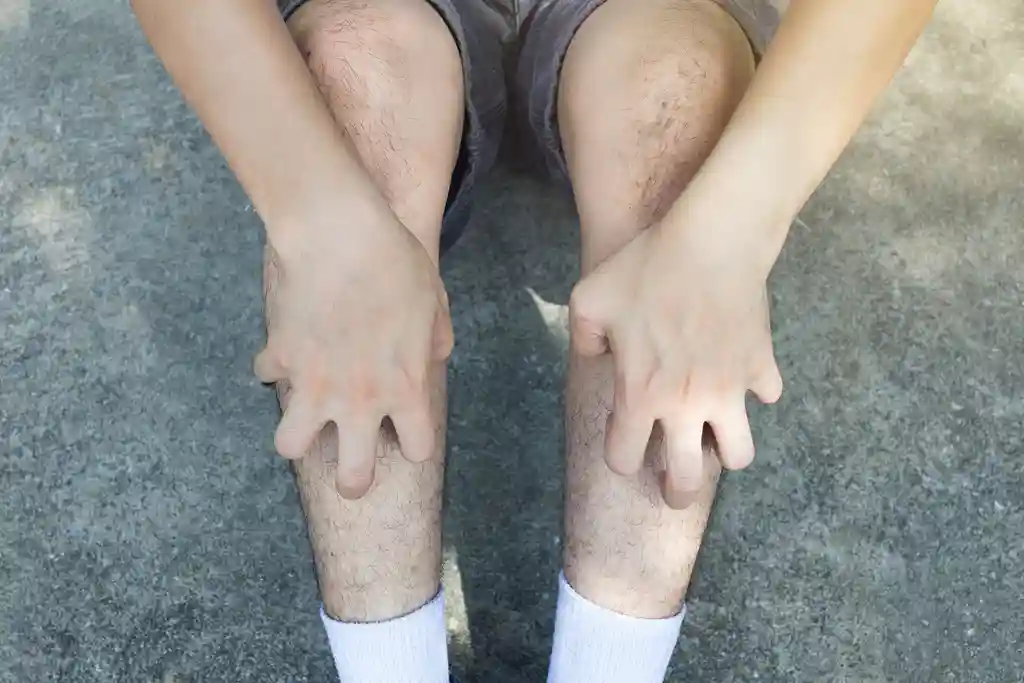 photo of man scratching legs