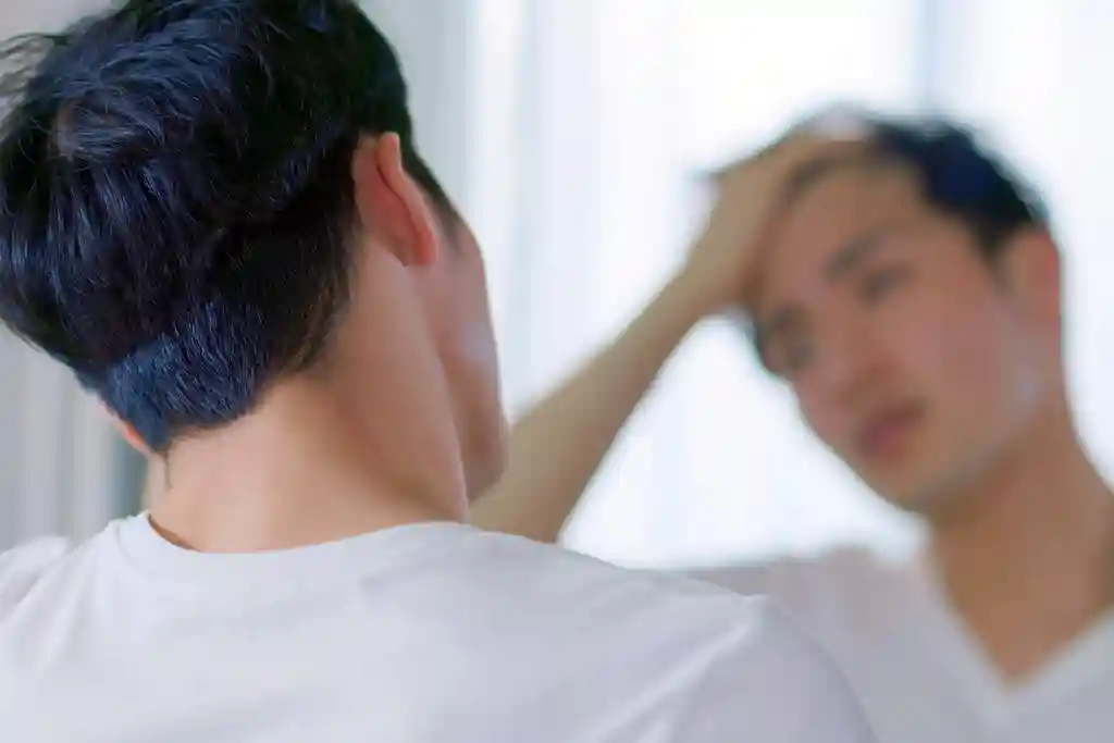 photo of man looking in mirror at hairline