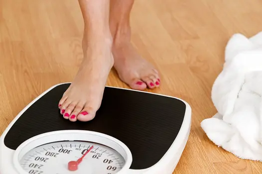 photo of young woman stepping on weight scale