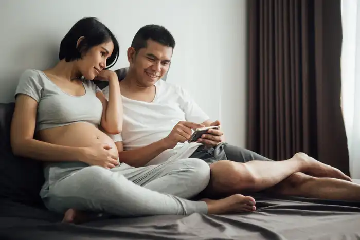 photo of pregnant couple watching smartphone video