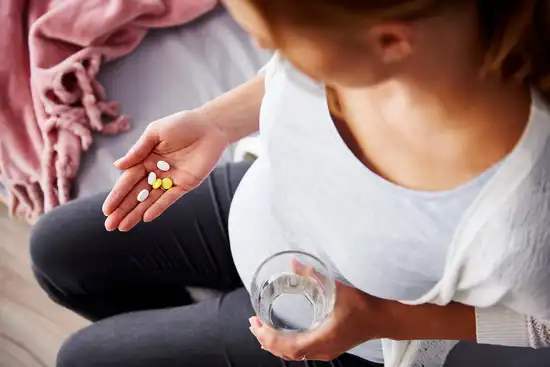 photo of pregnant woman taking vitamins