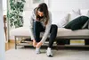 photo of woman putting on sport shoes at home