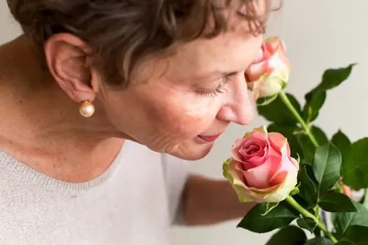 mature woman smelling roses