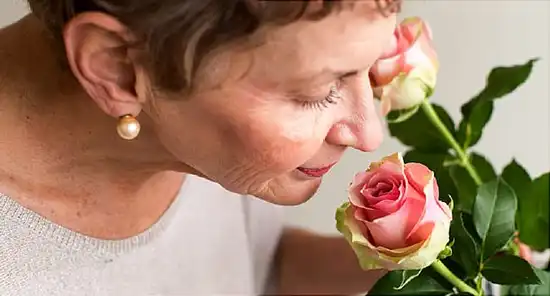 mature woman smelling roses