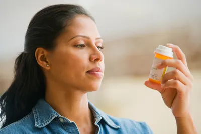 photo of woman looking at medicine bottle